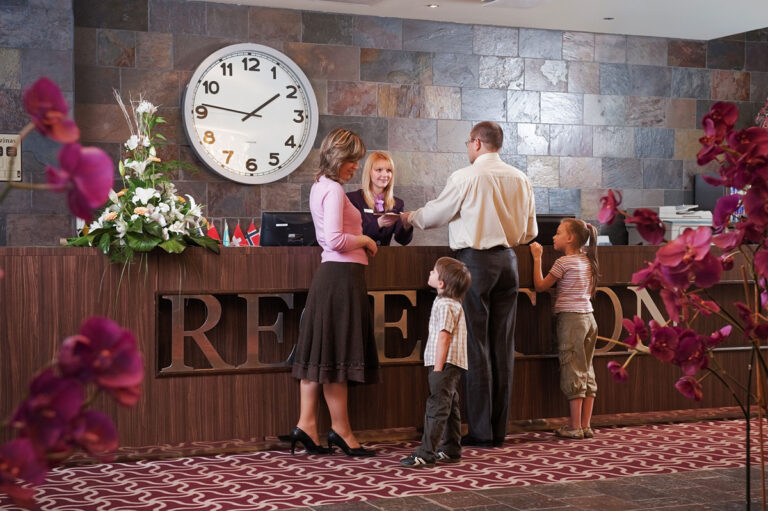 A family of four booking a hotel and a receptionist.