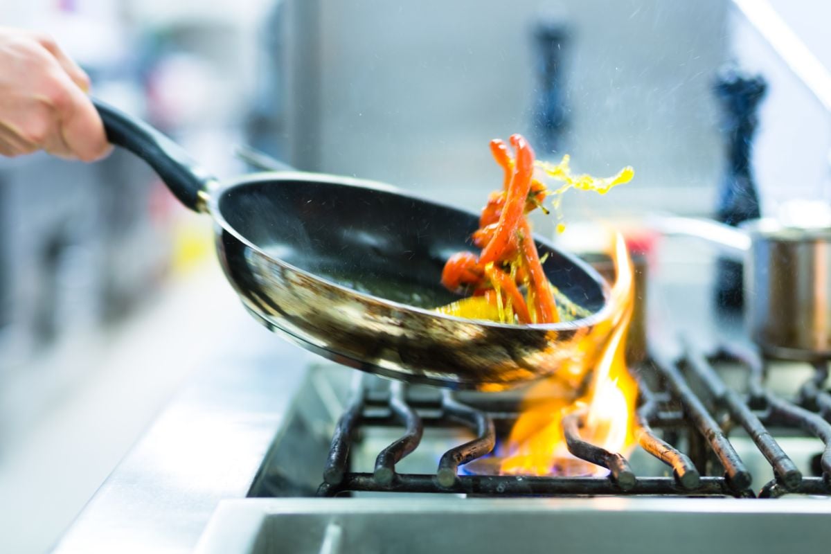 A person cooking a meal using a pan.