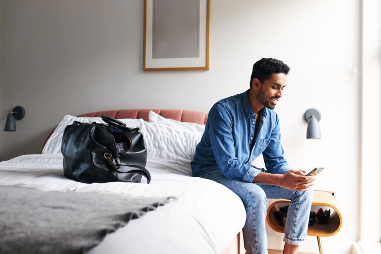 A man sitting on a bed in the hotel.