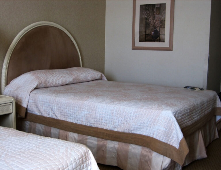 A Hotel room with beds covered with comforter.