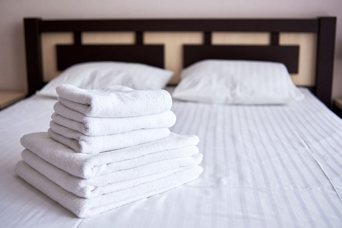 A bed with bath towel and linens.