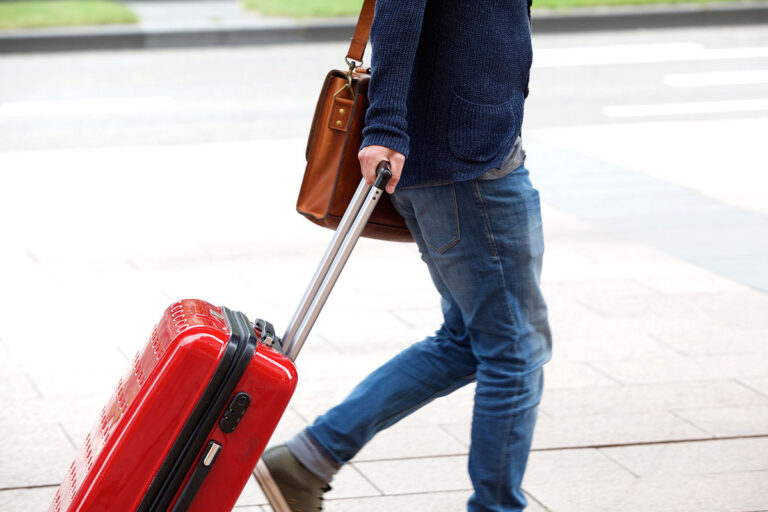 A person with jeans carrying a red bag.