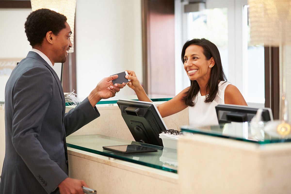 A man handing out a card to a receptionist.