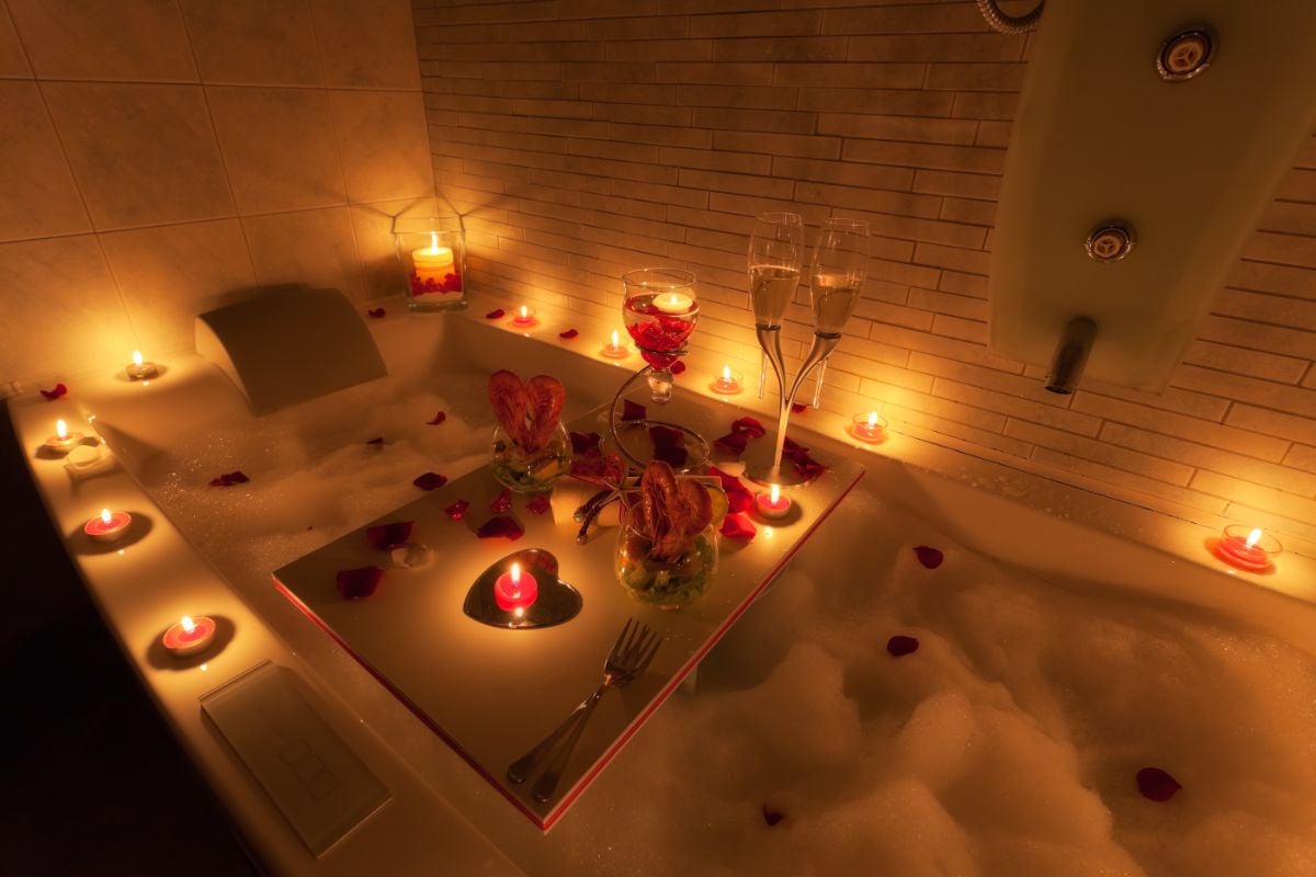 A bath tub with candle lights and wine.