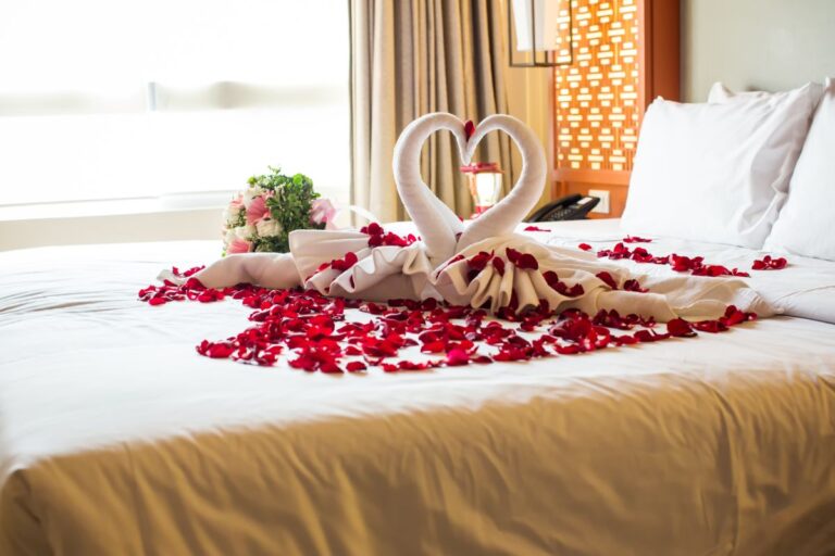 A bed with rose petals and swan designs.