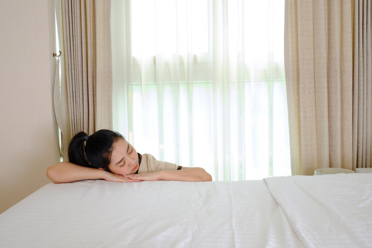 A hotel staff lying on the bed sleeping.