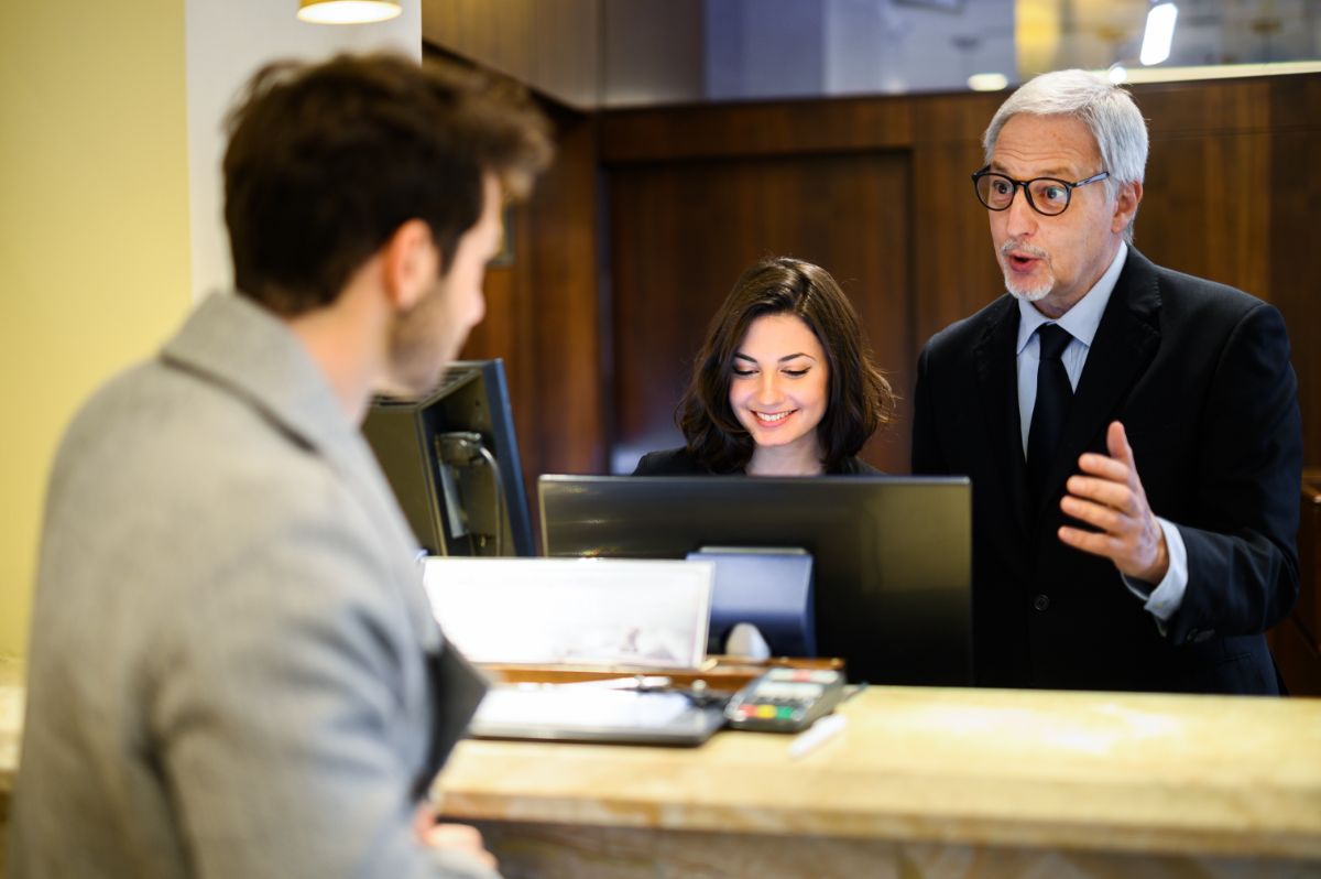 An old hotel staff and a guest in the front desk.