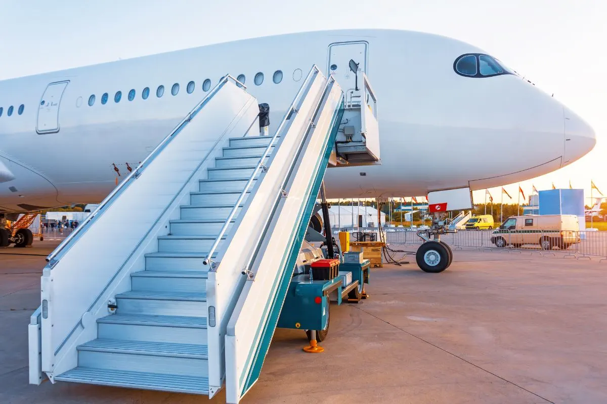 A commercial plane with stairs at the airport.