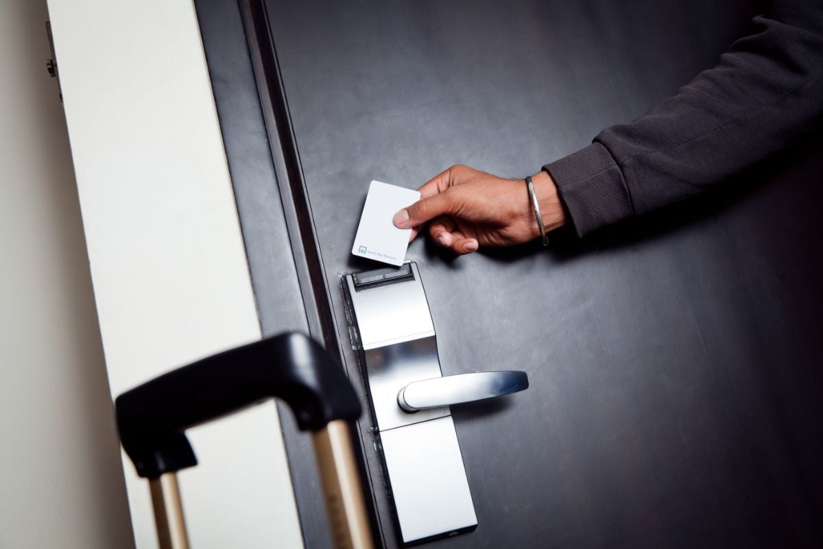 A person with his luggage opening a hotel room.