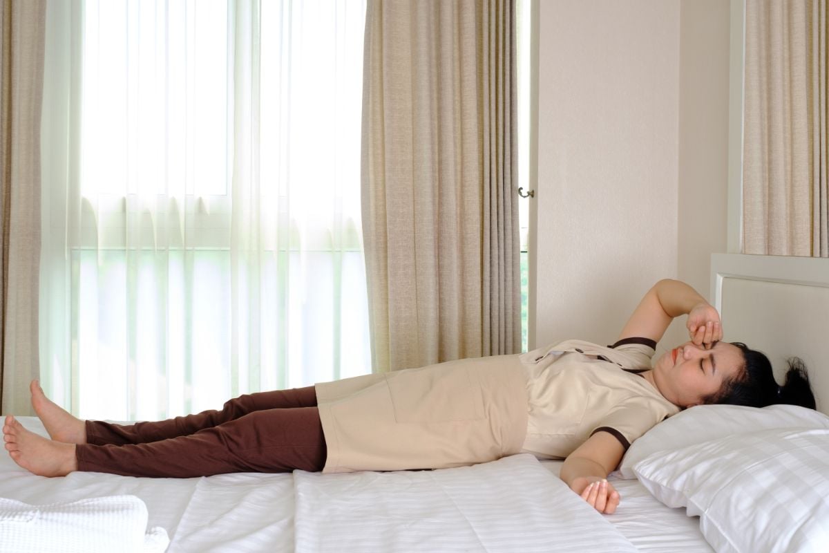 A hotel staff sleeping on a hotel bed.