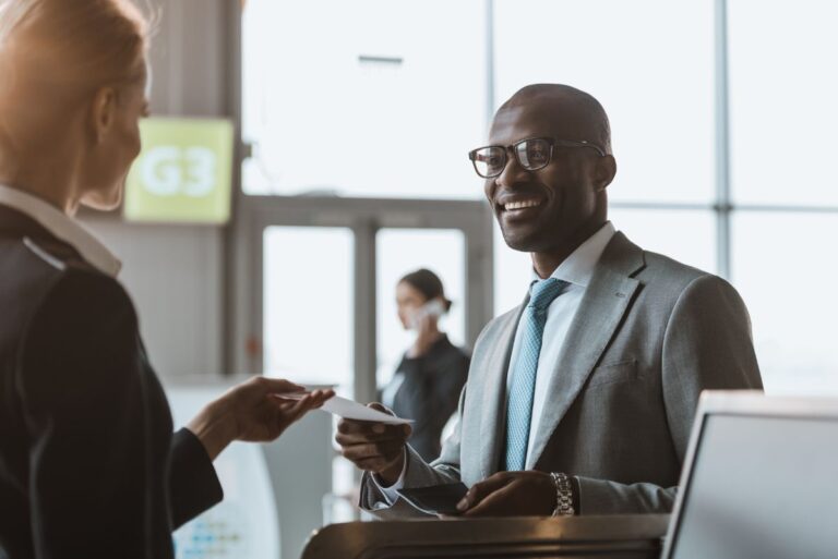 A business man handing a piece of paper to the receptionist.