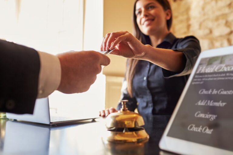 A woman in the front desk handing a credit card to a guest.