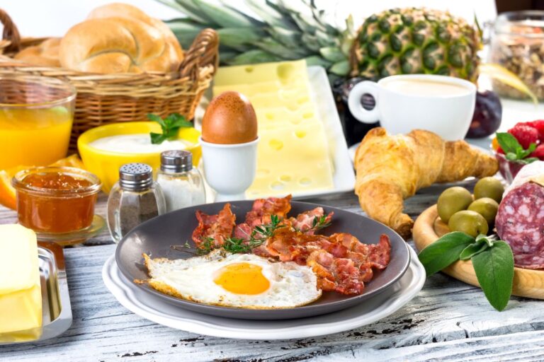 Hotel breakfast with eggs, bacon and fruits.