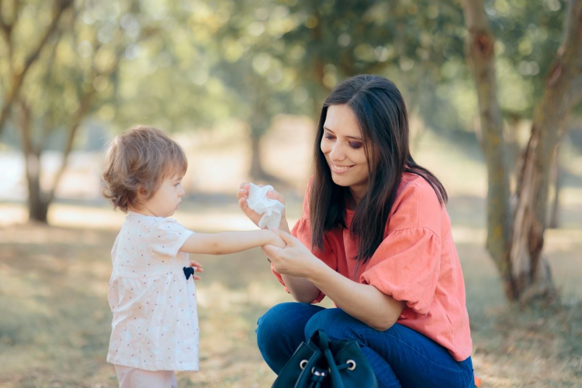 A woman wiping the hand of her daughter.