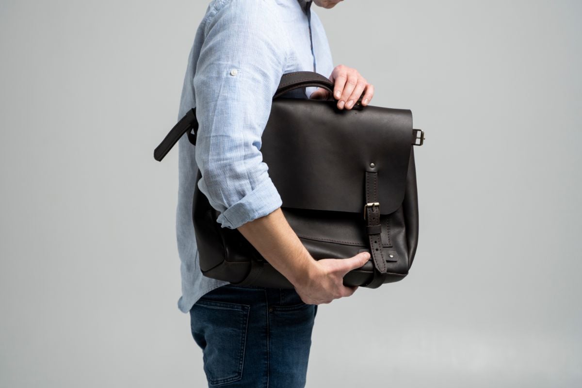 A man holding a Messenger Bag Backpack.