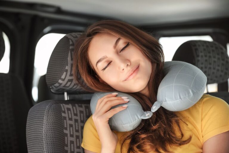 A woman on a car sleeping with travel pillow.