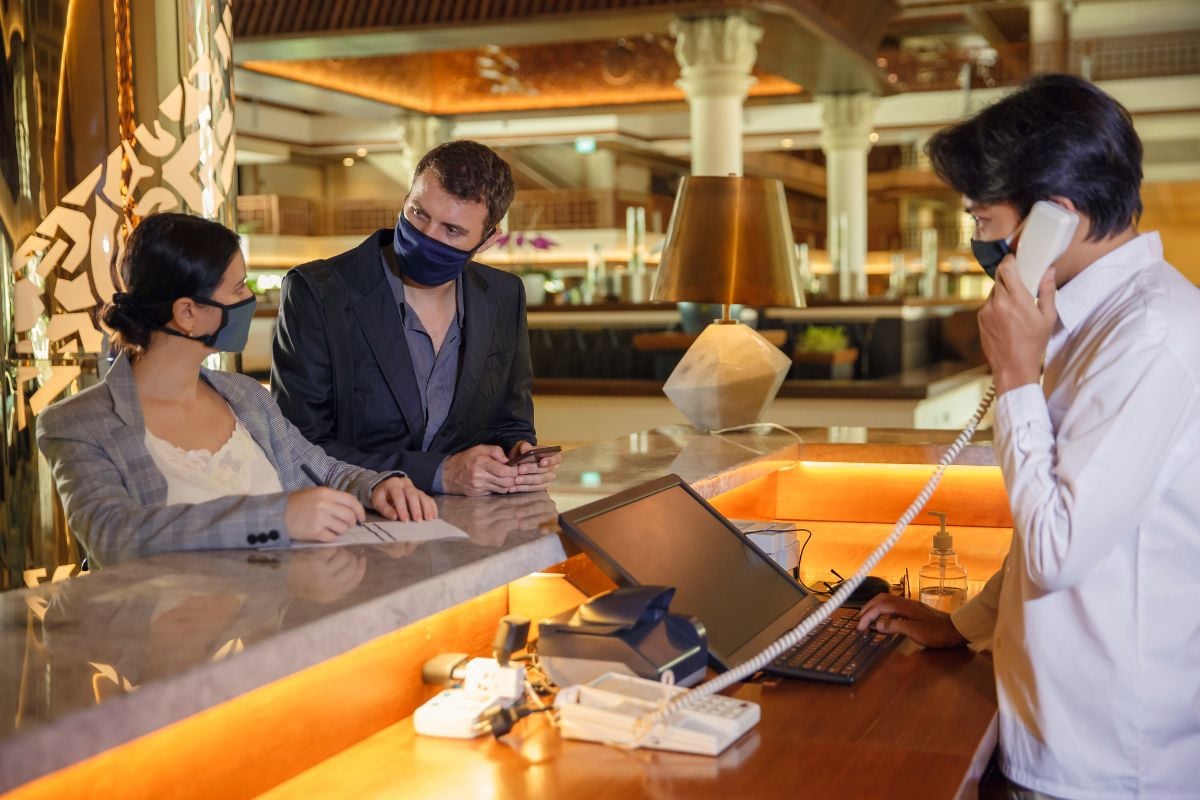 A couple in hotel front desk and a concierge on phone.