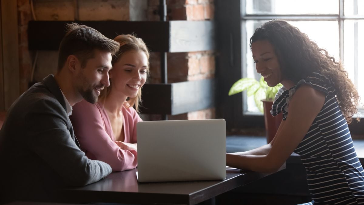 A couple and a travel agent on a laptop.