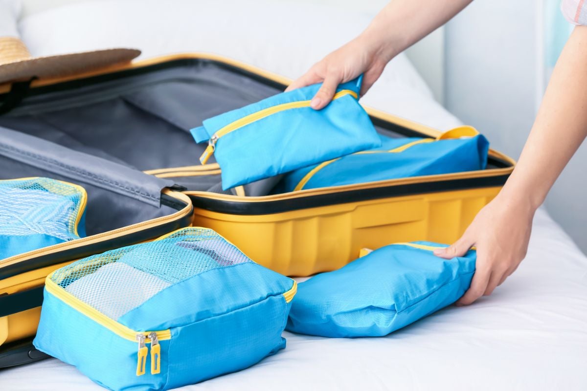 A person packing luggage with packing organizers.