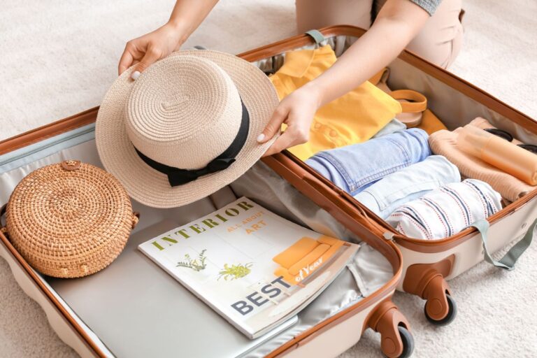 A woman placing a hat on a travel bag.