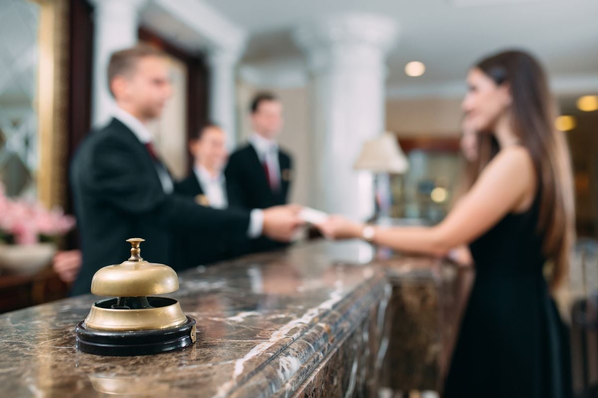 A call bell and a hotel guest handing a paper to front desk.