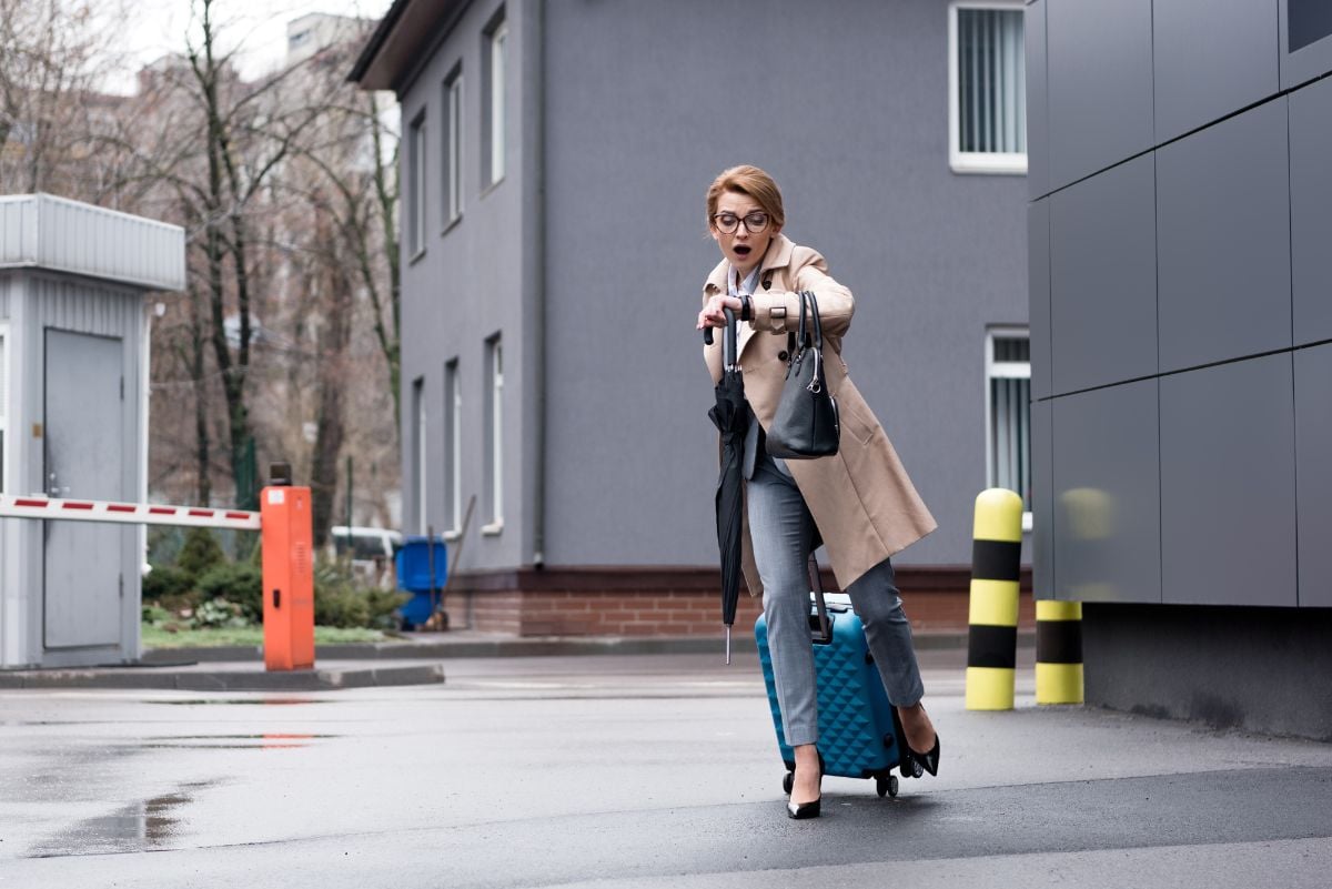 A woman running on the street with her luggage.