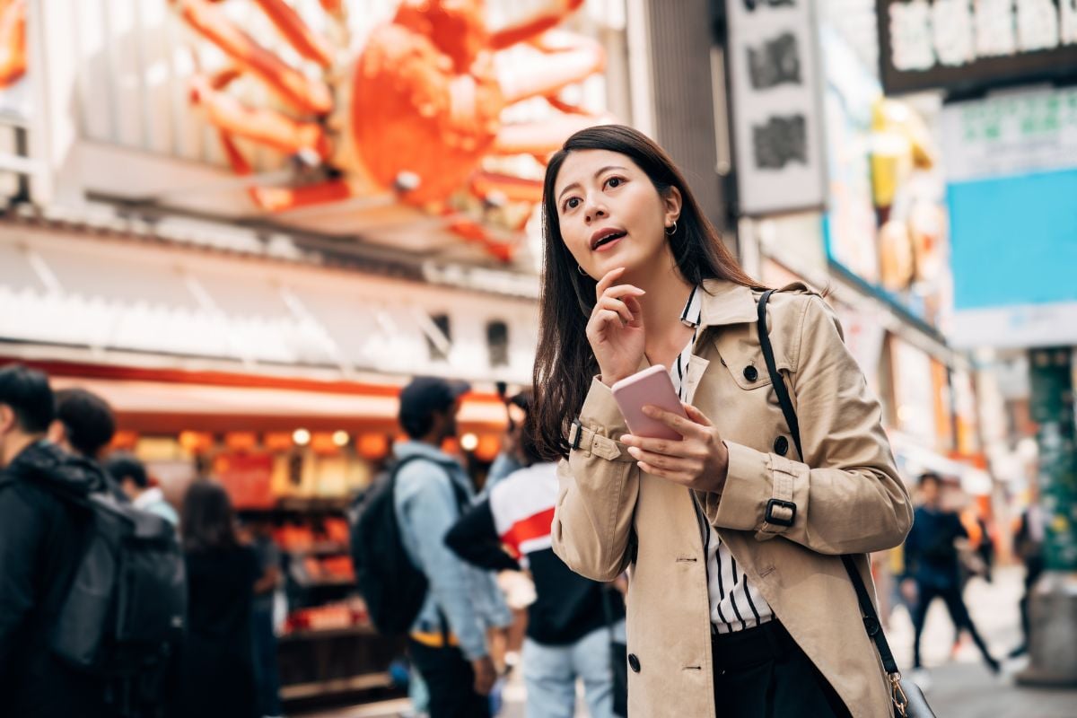 A woman holding her smartphone while walking on the street.