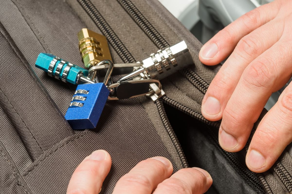 A person opening a bag with combination locks.