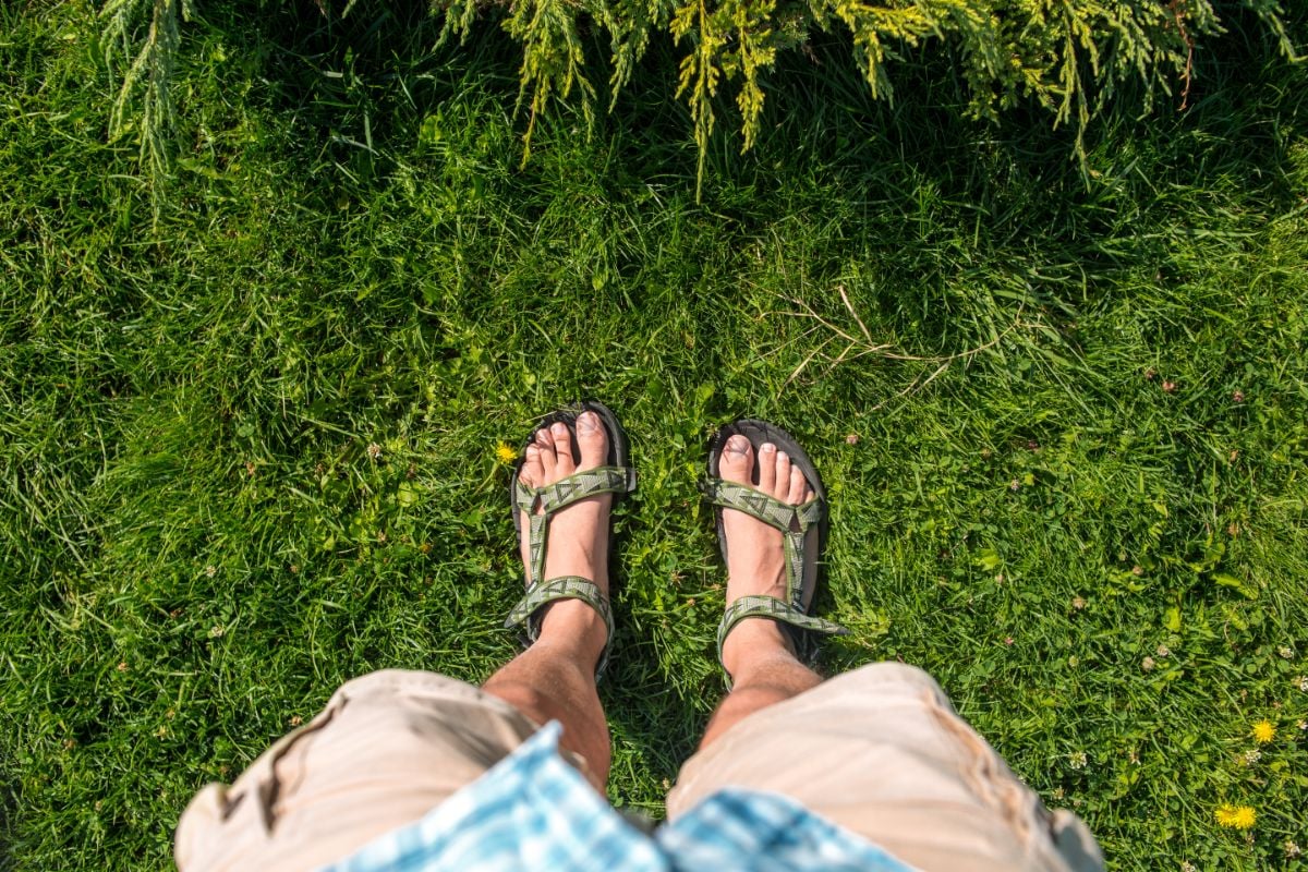 A person standing on the grasses wearing sandals.