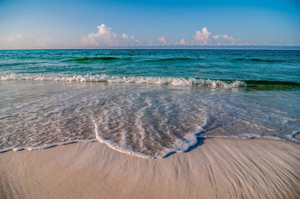 A beach with white sand blue waves.