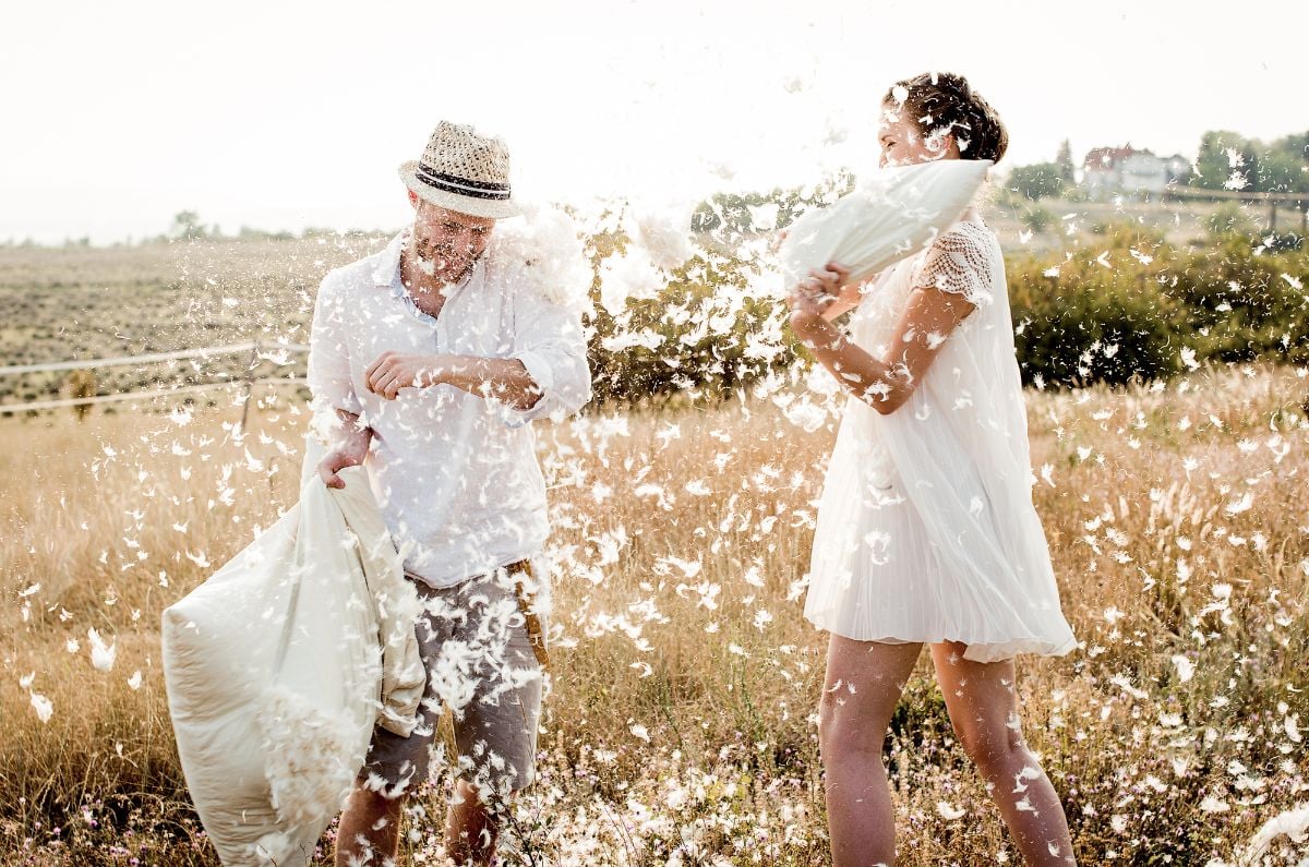 A happy couple having a pillow fight outdoor.