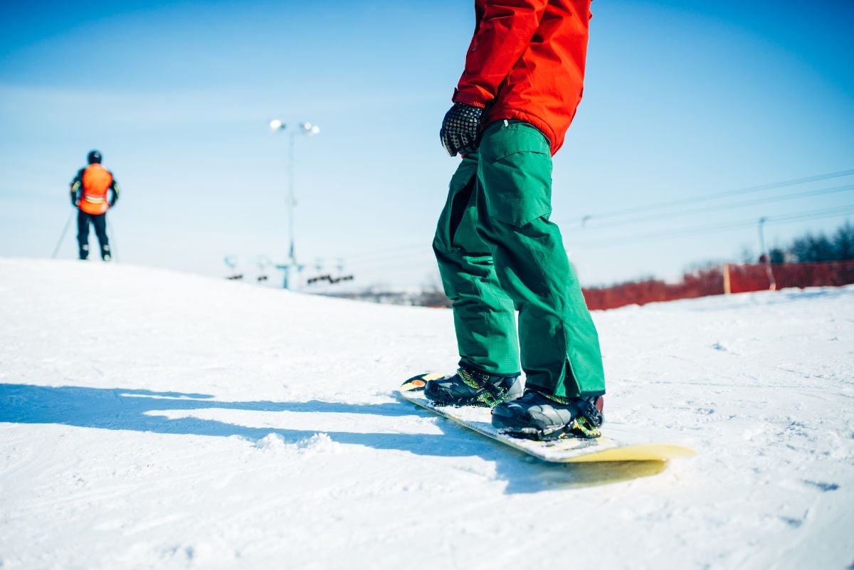 snowboarder wearing a red jacket and green snow pants on a snowy hill