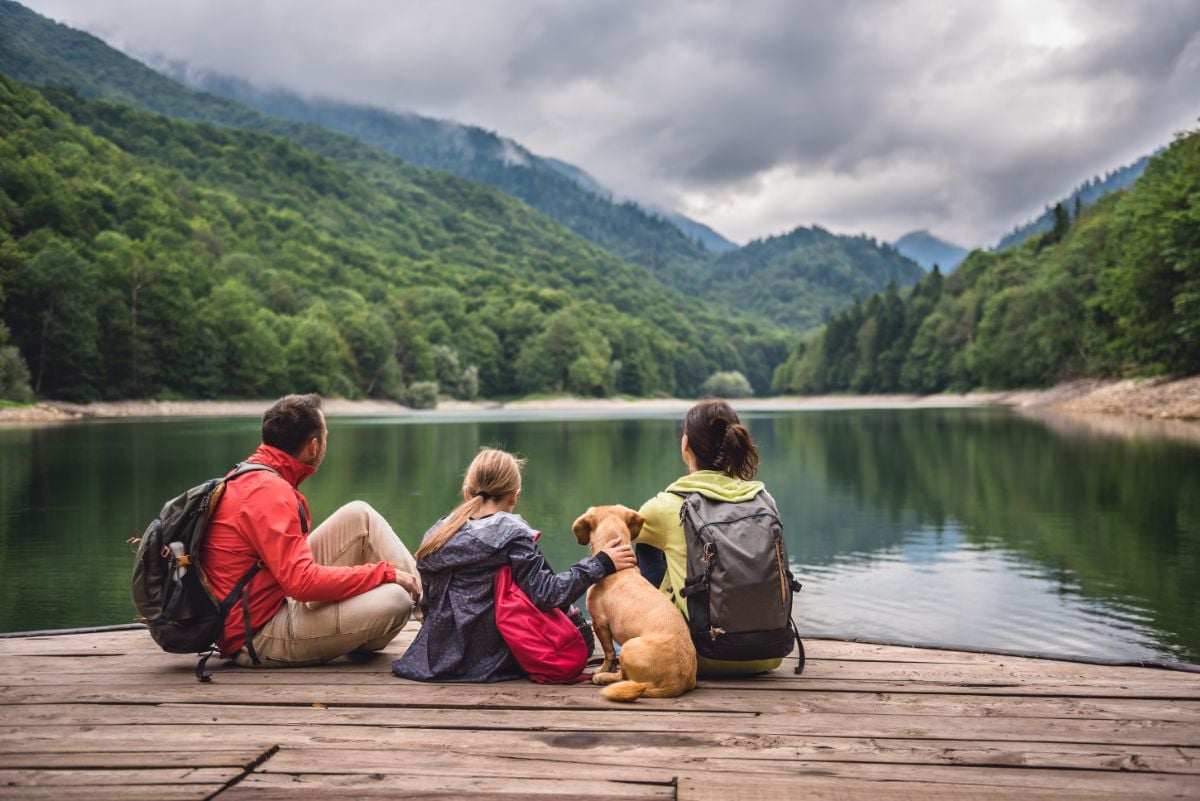 Couple with a dog sitting on a dock by the lake